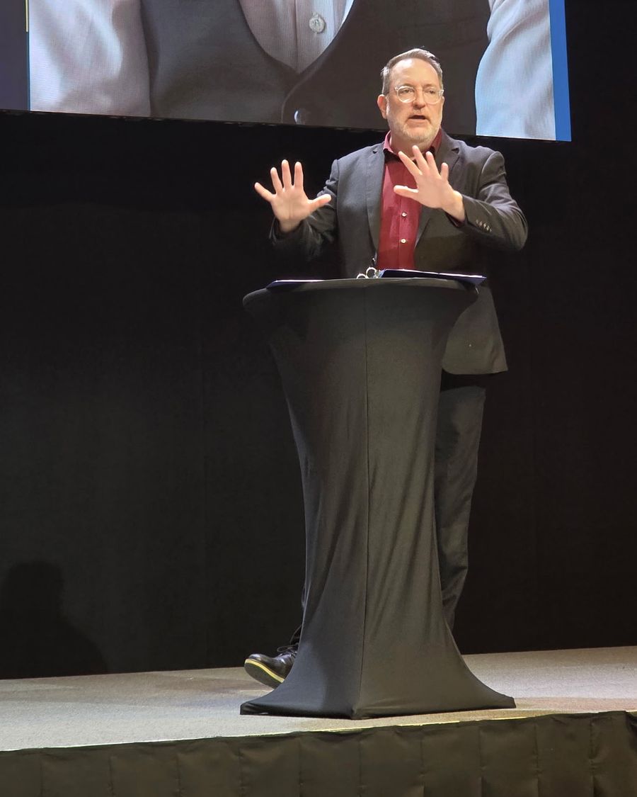 Dave Groves speaking at a podium on stage